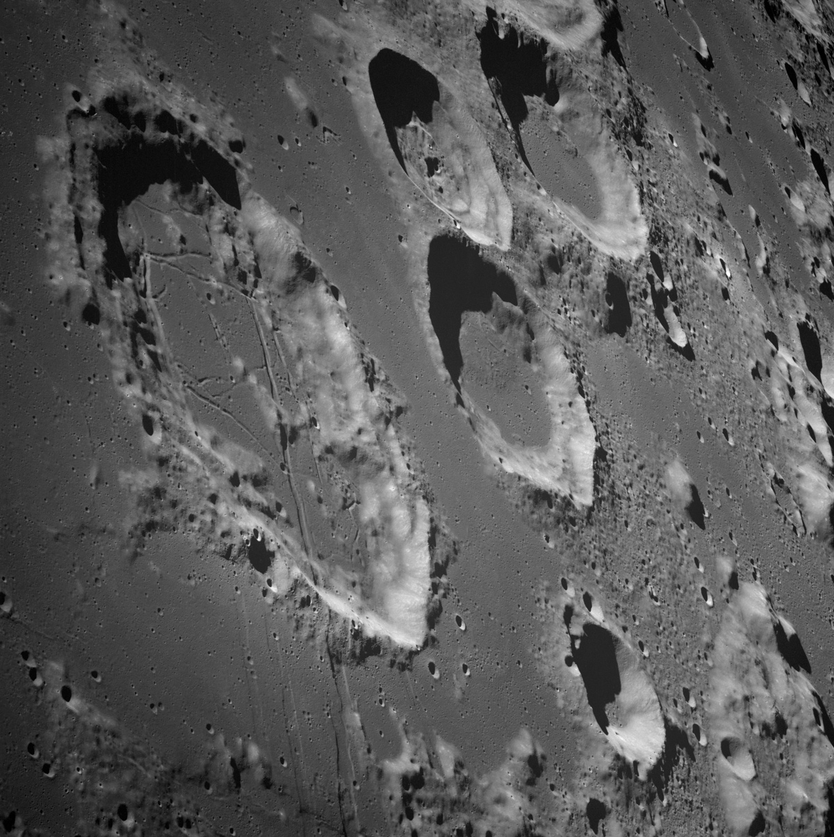 Craters dot the Moon's landscape. This photograph was taken from the Apollo 8 spacecraft with long-focal length lens, looking south at the large crater Goclenius, which is in foreground. Hold picture with Goclenius at bottom center. The three clustered craters are Magelhaens, Magelhaens A, and Colombo A. The crater at upper right is Gutenberg D. The crater Goclenius is located at 10 degrees south latitude, 45 degrees east longitude, and it is approximately 40 statute miles in diameter. Image: NASA/JSC