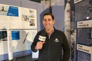 Garrett Marqua, a member of the brand management team of DoubleTree by Hilton, is interviewed at NASA Wallops, standing besides a model of the Northrop Grumman Antares rocket. It is this rocket that launched an oven that'll bake a DoubleTree cookie in space soon. Image: Weatherboy