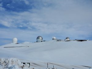 On a ridge just below the summit of Mauna Kea, several telescopes rise above the deep snow pack. Image: Weatherboy