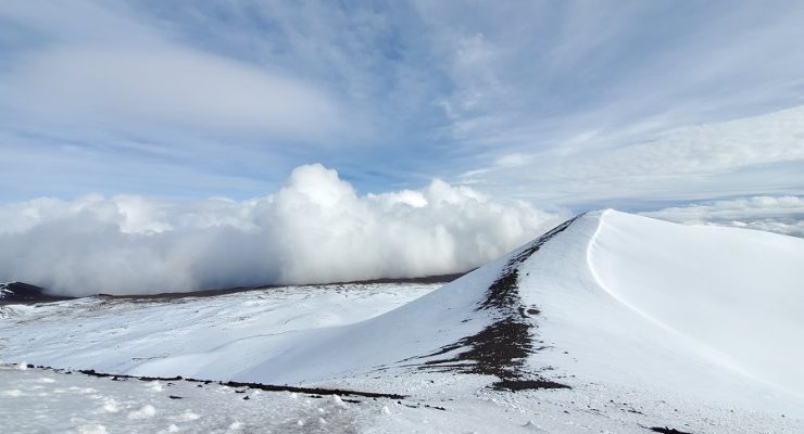 Clouds collide into the peak of Mauna Kea from the Hilo side of the mountain. The peak of the summit, which some consider culturally or spiritually significant, is on the right, free of any telescopes or roads. Image: Weatherboy