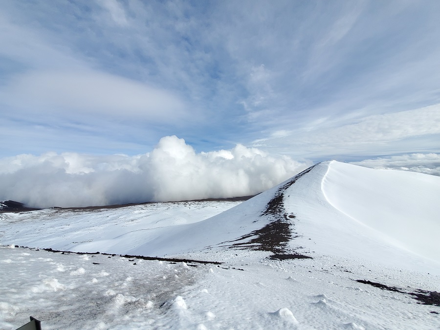 Clouds collide into the peak of Mauna Kea from the Hilo side of the mountain. The peak of the summit, which some consider culturally or spiritually significant, is on the right, free of any telescopes or roads. Image: Weatherboy