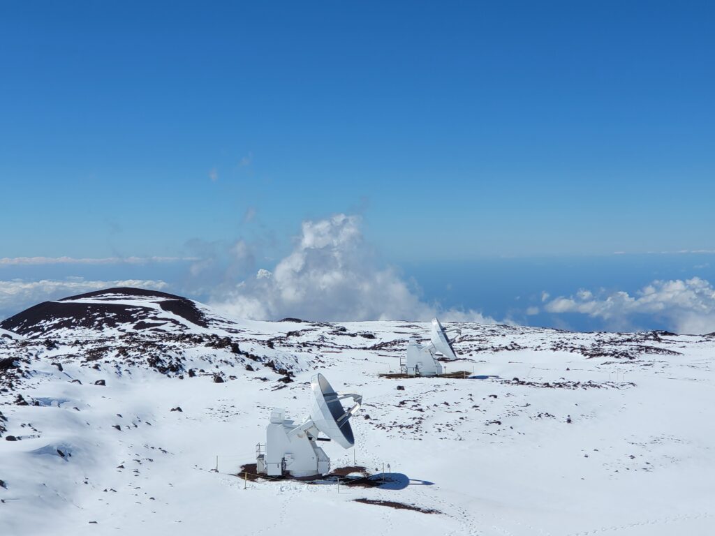 Radio telescopes dot the landscape atop Mauna Kea, surrounded by deep snow. The Thirty Meter Telescope, which would be the largest telescope in the Northern Hemisphere, is due to be built on the plateau to the left of these radio telescopes. Image: Weatherboy