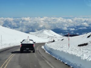A pick-up truck filled with snow heads down the snow-plowed Mauna Kea Access Road. Image: Weatherboy