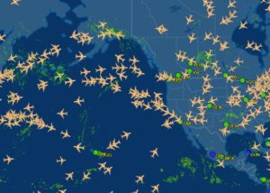 Flight tracking website FlightAware shows the 12 noon ET position of aircraft over North America and adjacent ocean waters of the Pacific. Each plane icon marks aircraft in-flight; airports and their airport codes are highlighted on the map. Image: FlightAware.com
