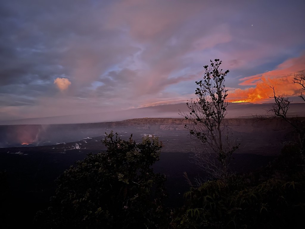 This picture, taken at 6:06 am Monday, November 28 from Kūpinaʻi Pali in Hawaii Volcanoes National Park, shows red glow coming off of the smaller Kilauea eruption to the right, with the much more impressive and larger eruption and lava flow of Mauna Loa visible on the right. Image: NPS / J. Ibasan