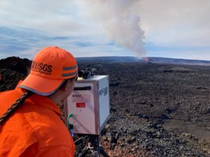 A USGS Hawaiian Volcano Observatory gas specialist uses a FTIR spectrometer on the Northeast Rift Zone of Mauna Loa during the 2022 eruption. The FTIR measures the composition of the gases being emitted during the eruption by measuring how the plume absorbs infrared energy. The plume being generated by the ongoing eruption is sulfur-dioxide (SO2) rich, but also contains water vapor, carbon dioxide, and halogen gases such as HCl and HF. Image: USGS/M. Patrick.