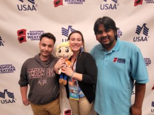 Shane Lewis, left, Sydney Ann Brown, center, and Rubayet Bin Mostafiz, right, pose with the Weatherboy mascot at the 2022 National Tropical Weather Conference in South Padre Island, Texas. Image: Weatherboy