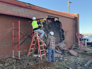 Workers inspect and make initial repairs on a National Weather Service office where a vehicle penetrated the building. Image: NWS