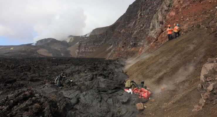 On July 2, three USGS Hawaiian Volcano Observatory scientists flew via helicopter to the northwest side of Halema‘uma‘u at the summit of Kīlauea to sample tephra deposits in the crater wall. These deposits were exposed by the 2018 summit collapse, but lava flows from the ongoing episodic Kīlauea summit eruption are likely to bury them again in the near future. Refilling the of the crater by eruptions in Halema‘uma‘u since 2020, including the ongoing episode lava fountaining eruption made it fairly easy to access the deposits, which just a few years ago were halfway up the cliff. The vent complex from the ongoing eruption can be seen in the distance on the left. Image: USGS / M. Zoeller